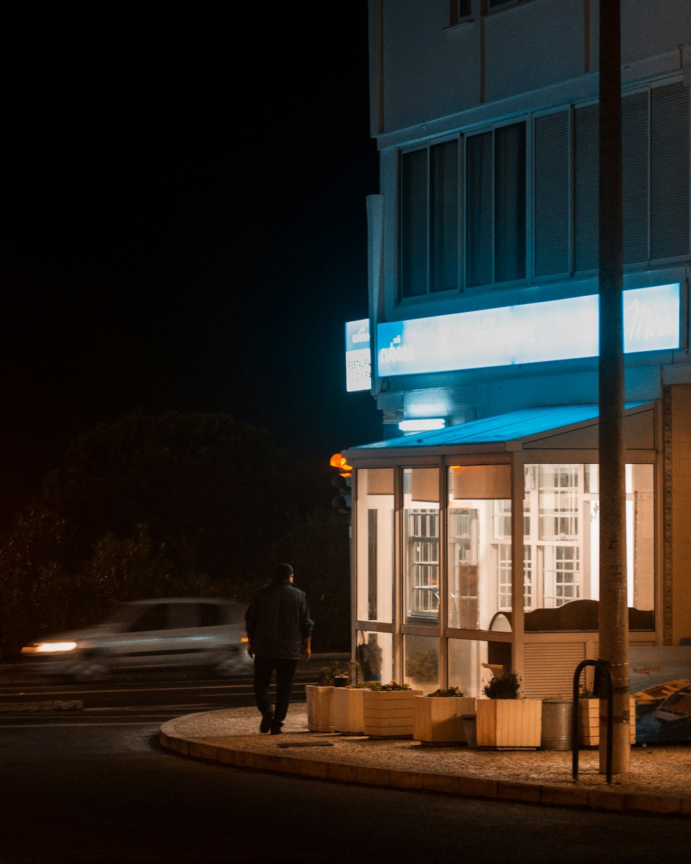 man in black jacket walking on sidewalk during night time