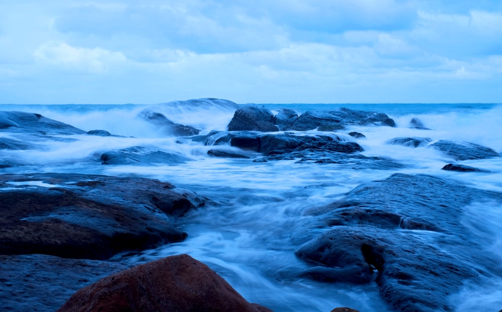 a body of water surrounded by rocks under a cloudy sky