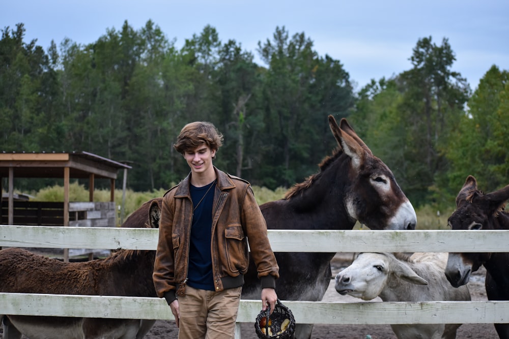 man in brown jacket standing beside brown and white horse during daytime