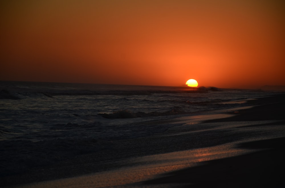 o sol está se pondo sobre o oceano na praia