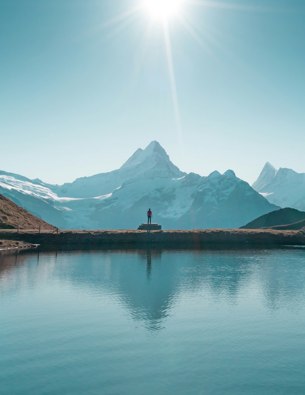 a person standing on a dock in front of a mountain