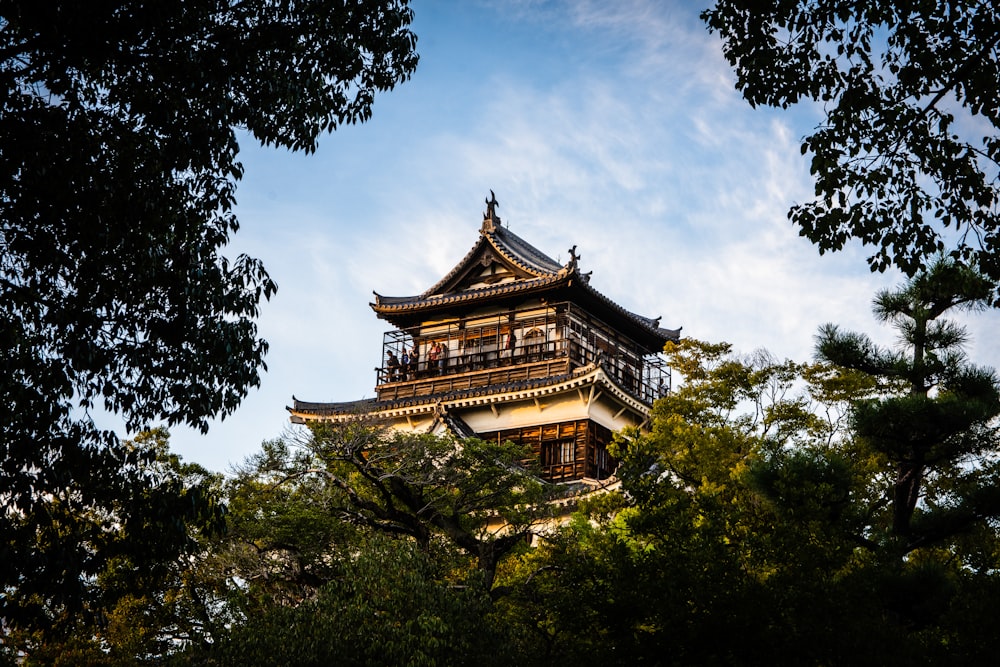 tempio marrone e bianco della pagoda circondato da alberi verdi sotto nuvole bianche e cielo blu durante