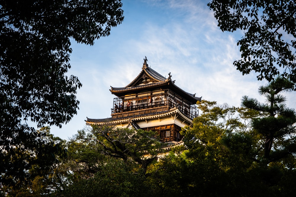 brown and white pagoda temple surrounded by green trees under white clouds and blue sky during