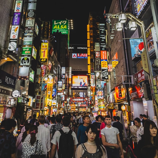 A lively urban night scene with neon lights and silhouettes of people meeting.
