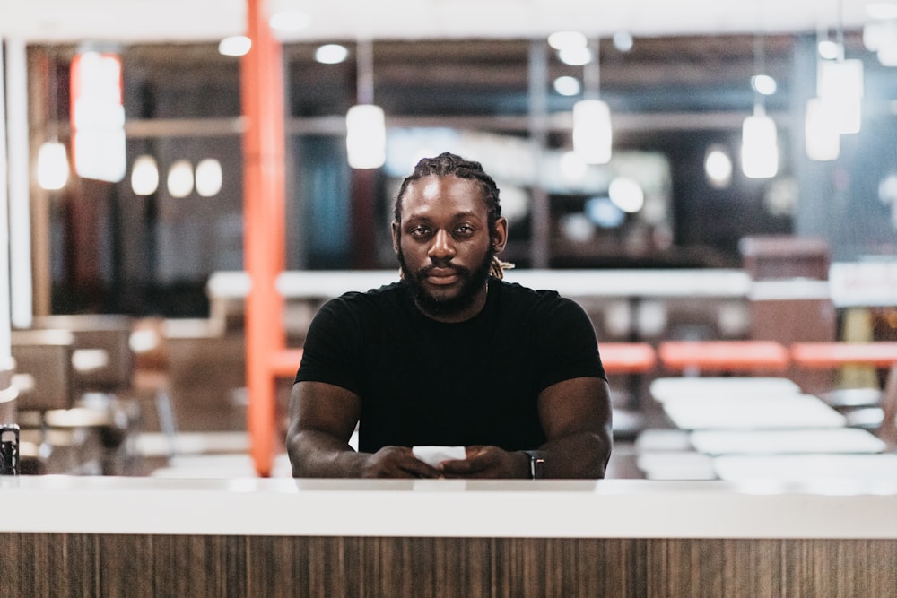 man in black crew neck t-shirt sitting by the table