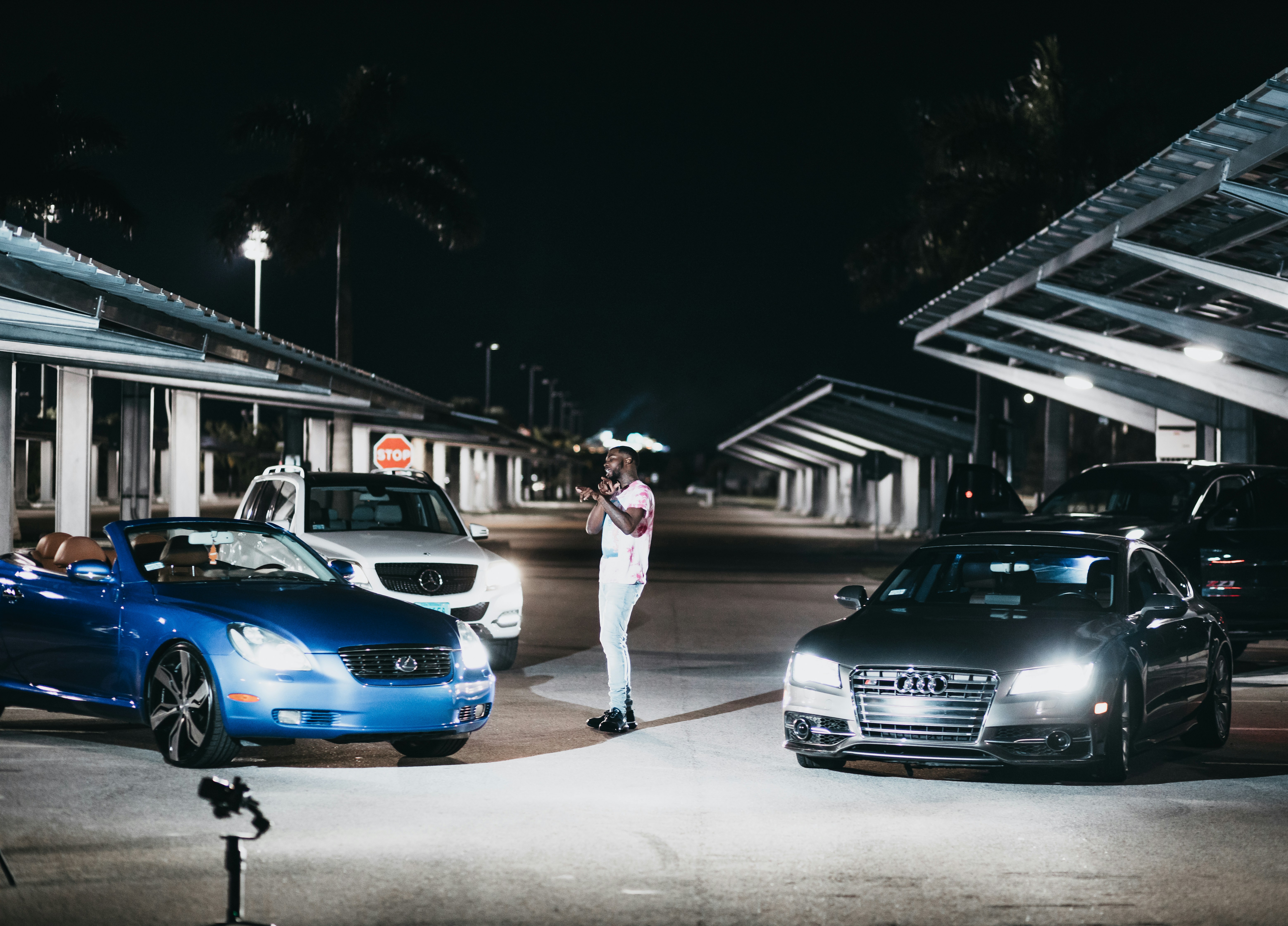 woman in white mini dress standing beside blue bmw car during night time