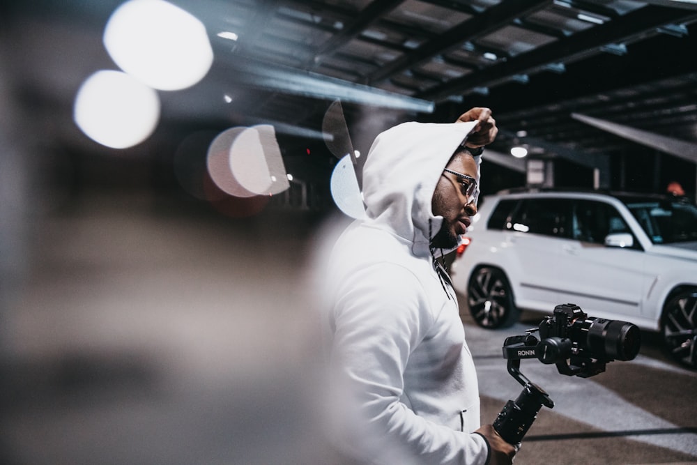 man in white long sleeve shirt holding black camera