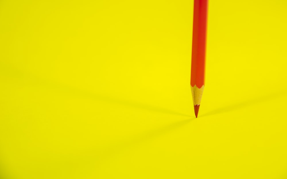 lápiz rojo sobre superficie amarilla