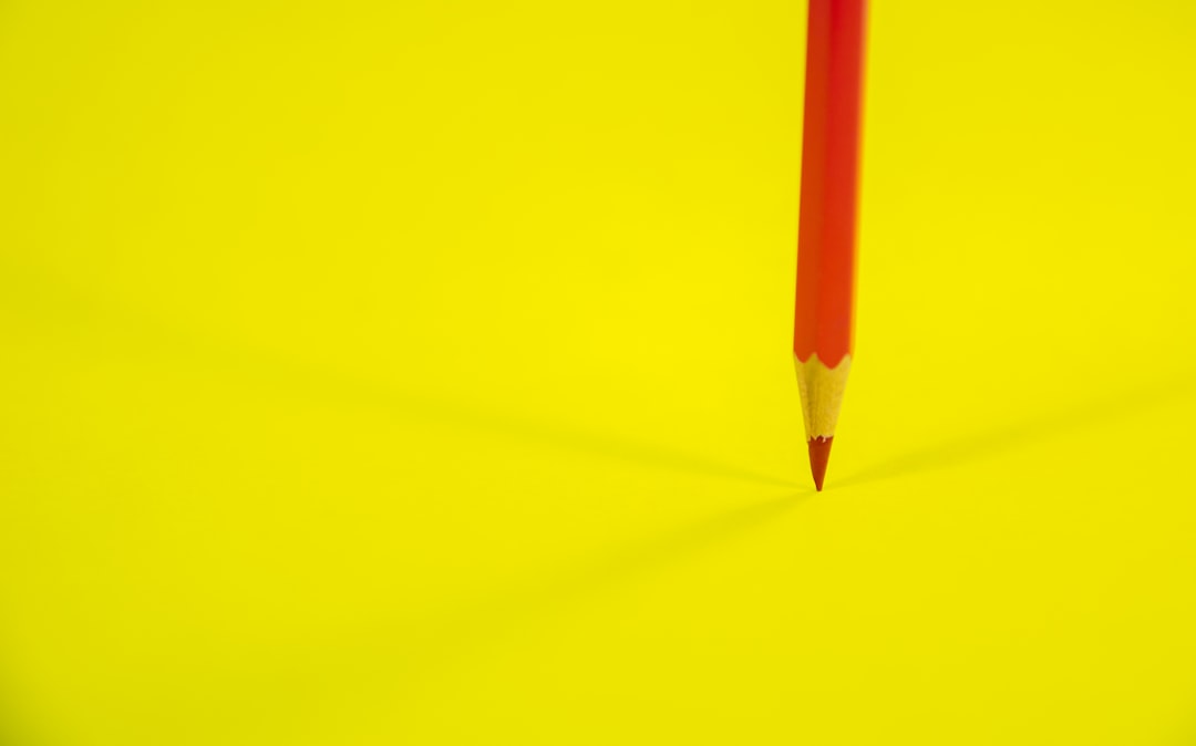 red pencil on yellow surface
