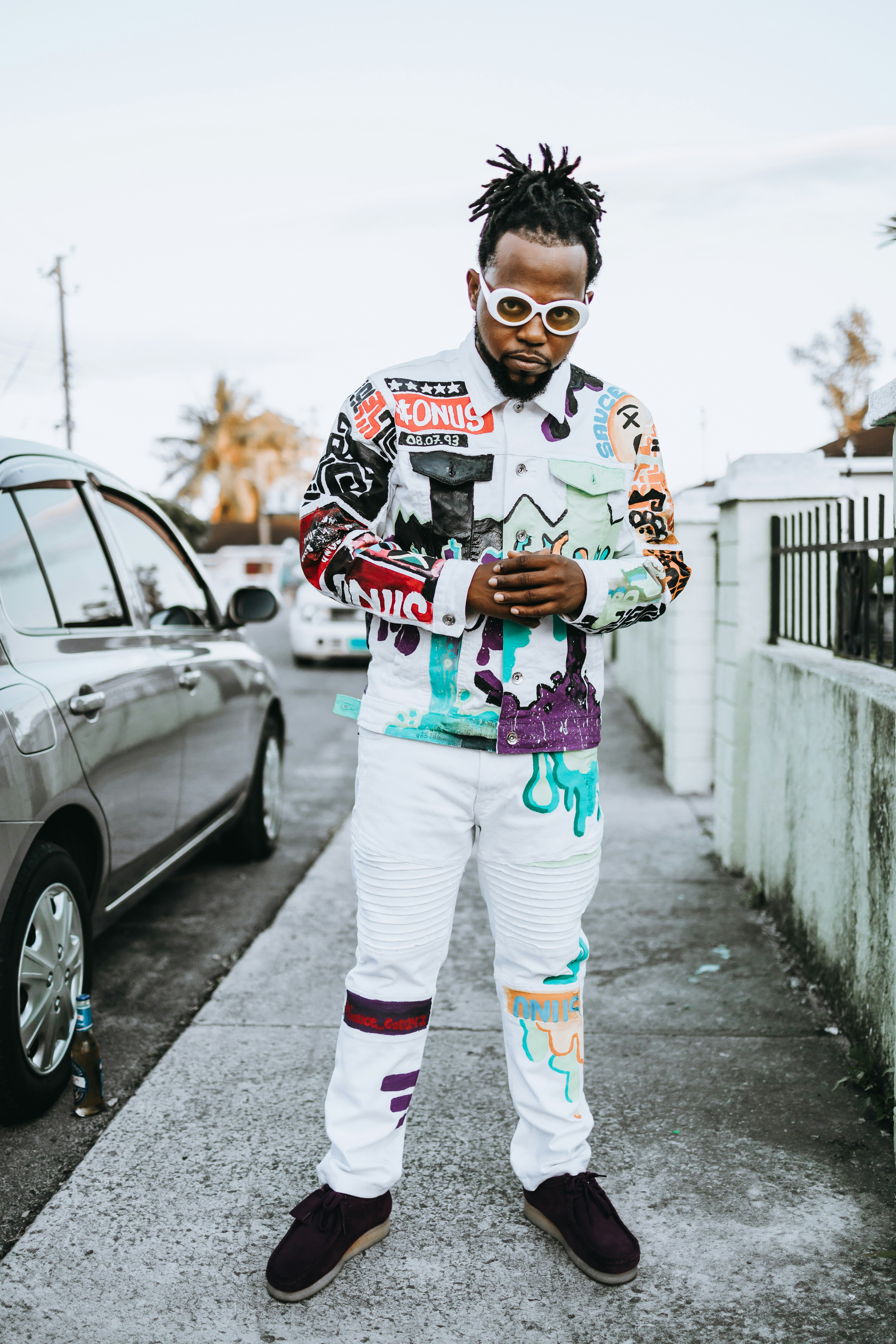 man in white and black long sleeve shirt and white pants standing on sidewalk during daytime