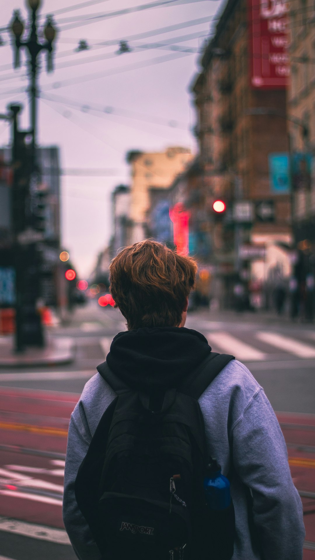 woman in black hoodie standing on sidewalk during daytime