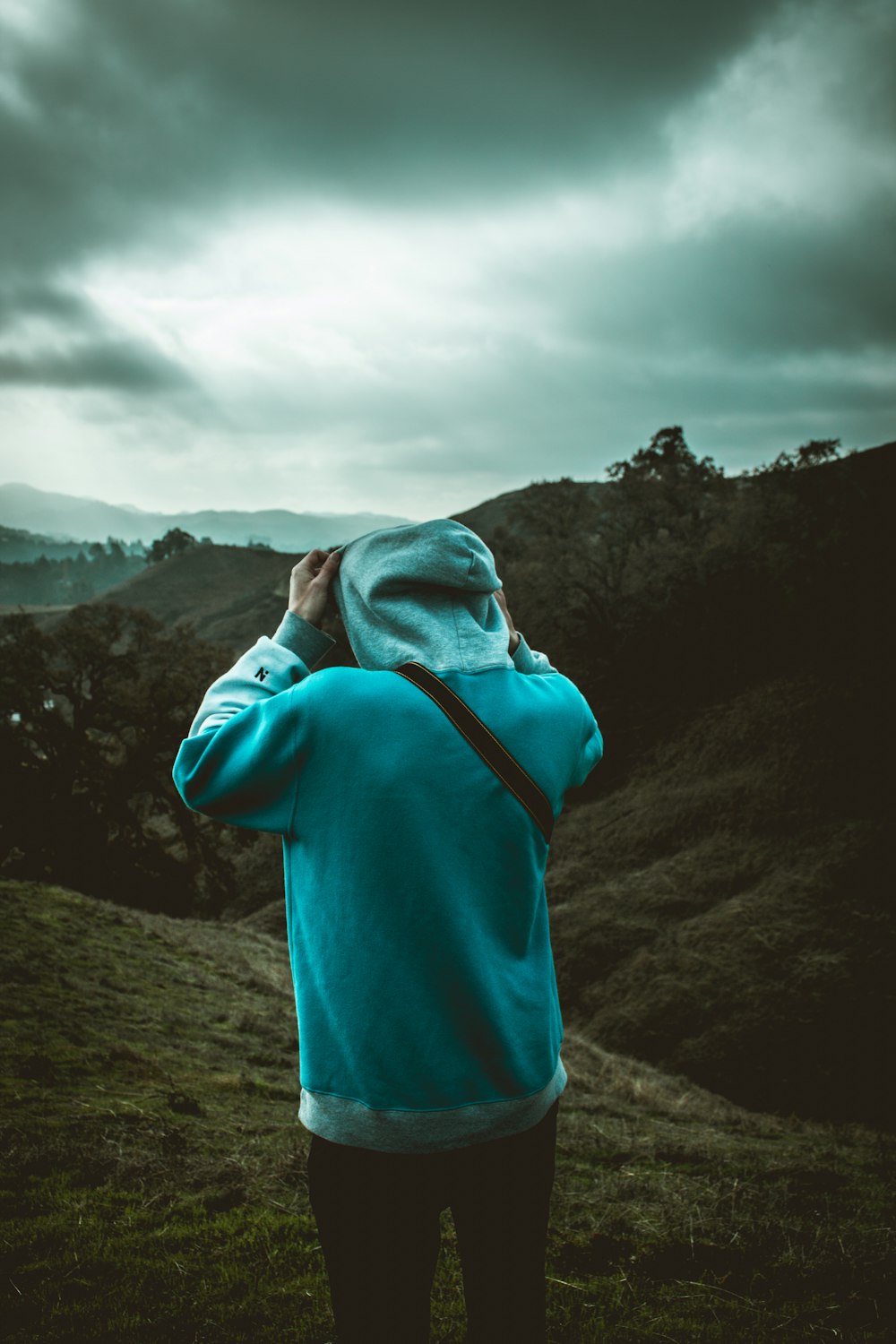 man in blue hoodie standing on hill