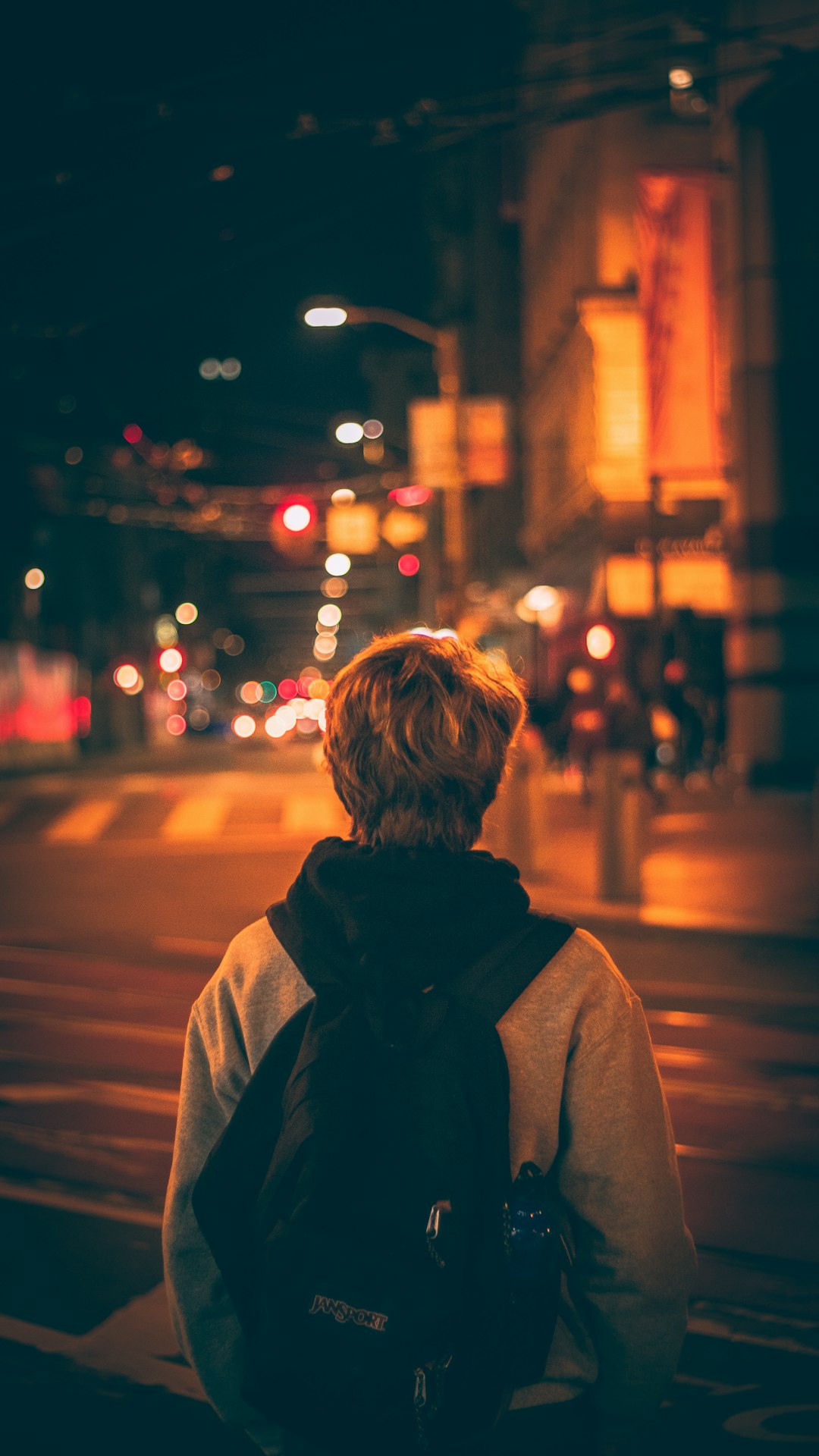 woman in gray coat standing on street during night time