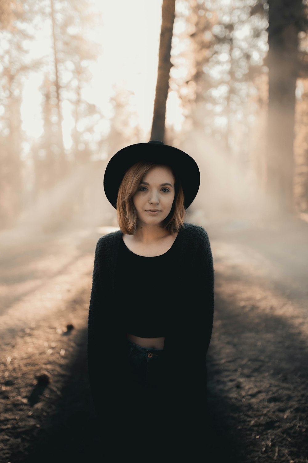 woman in black long sleeve shirt and black hat standing near brown tree during daytime