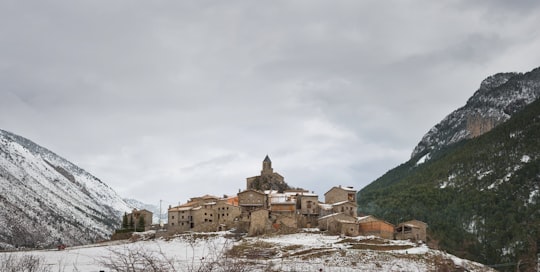 brown concrete building near green trees under white clouds during daytime in Josa de Cadí Spain