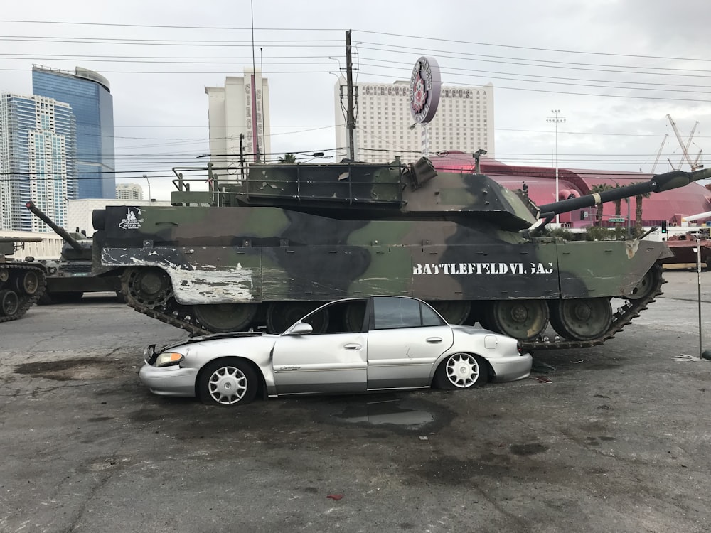 Weißes Coupé neben grünem Kampfpanzer geparkt