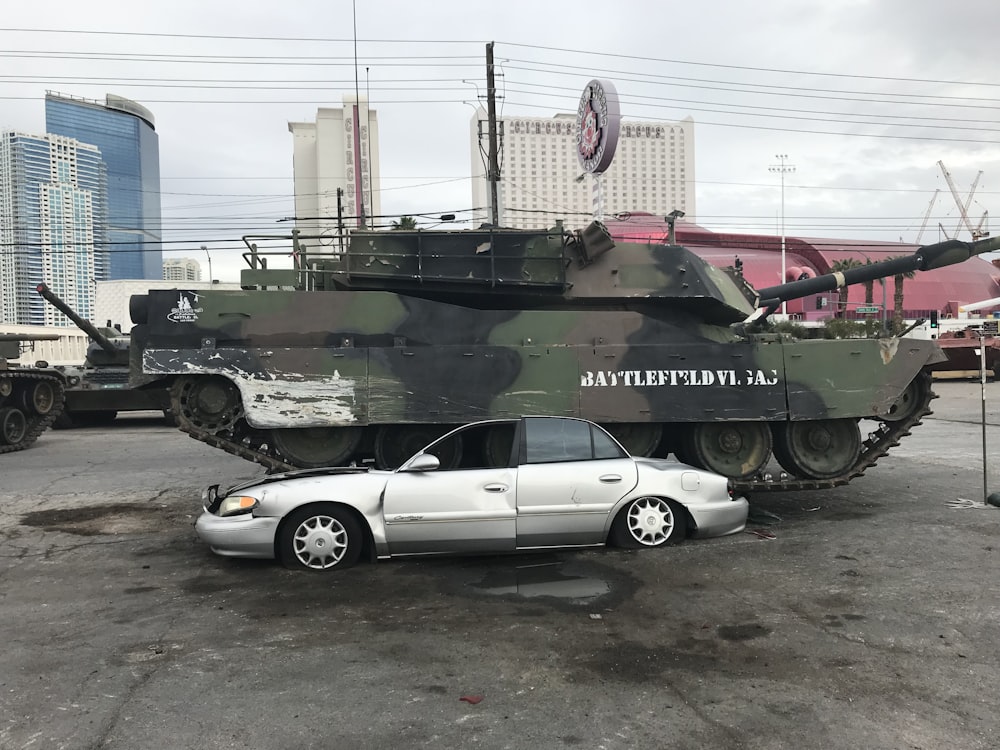 cupê branco estacionado ao lado do tanque de batalha verde