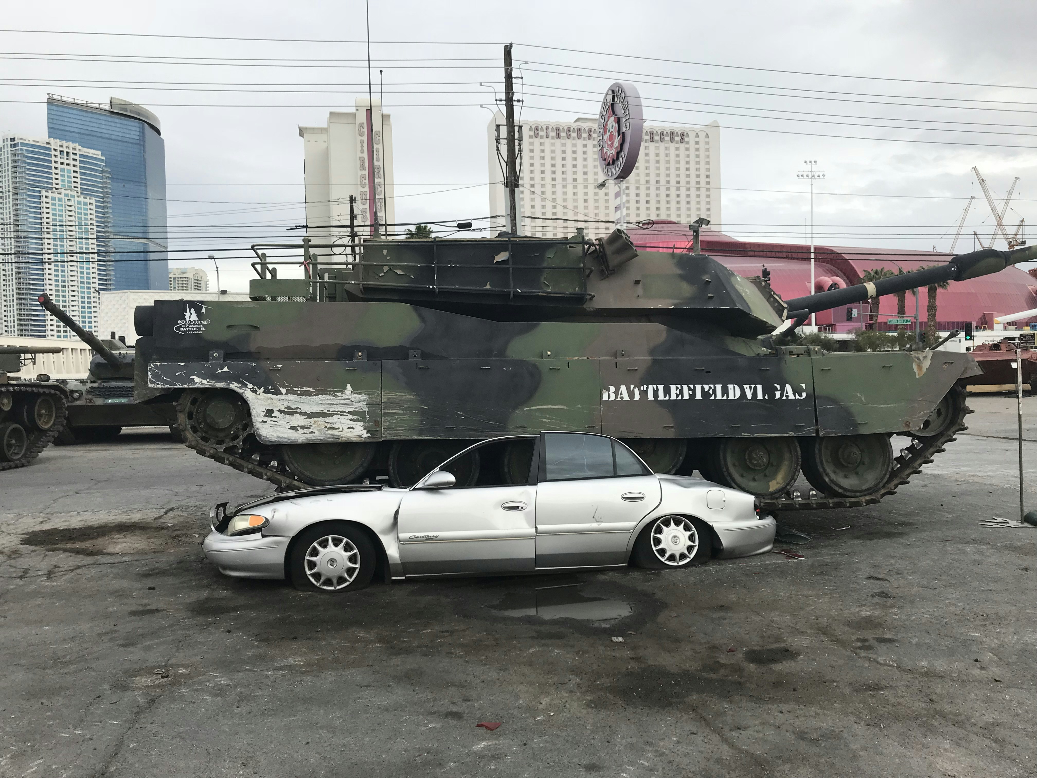white coupe parked beside green battle tank