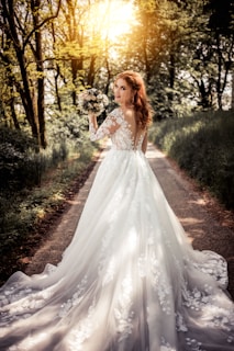 woman in white floral dress standing on brown soil surrounded by green plants and trees during