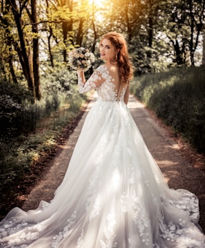 woman in white floral dress standing on brown soil surrounded by green plants and trees during