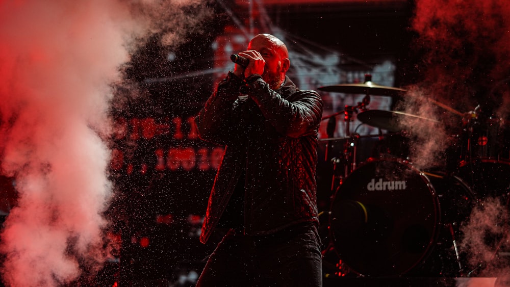 man in black jacket singing on stage