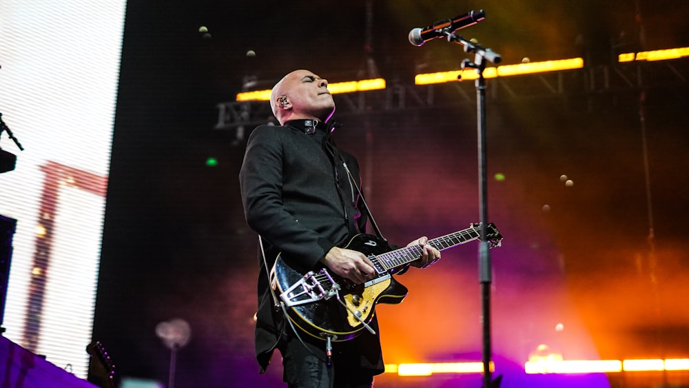 man in black jacket playing guitar