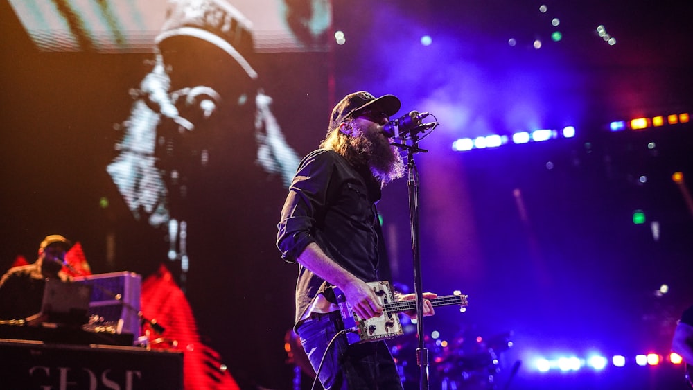 man in black leather jacket playing guitar on stage