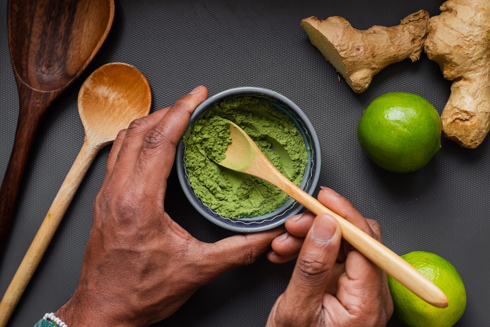 person holding brown wooden chopsticks and green round fruit