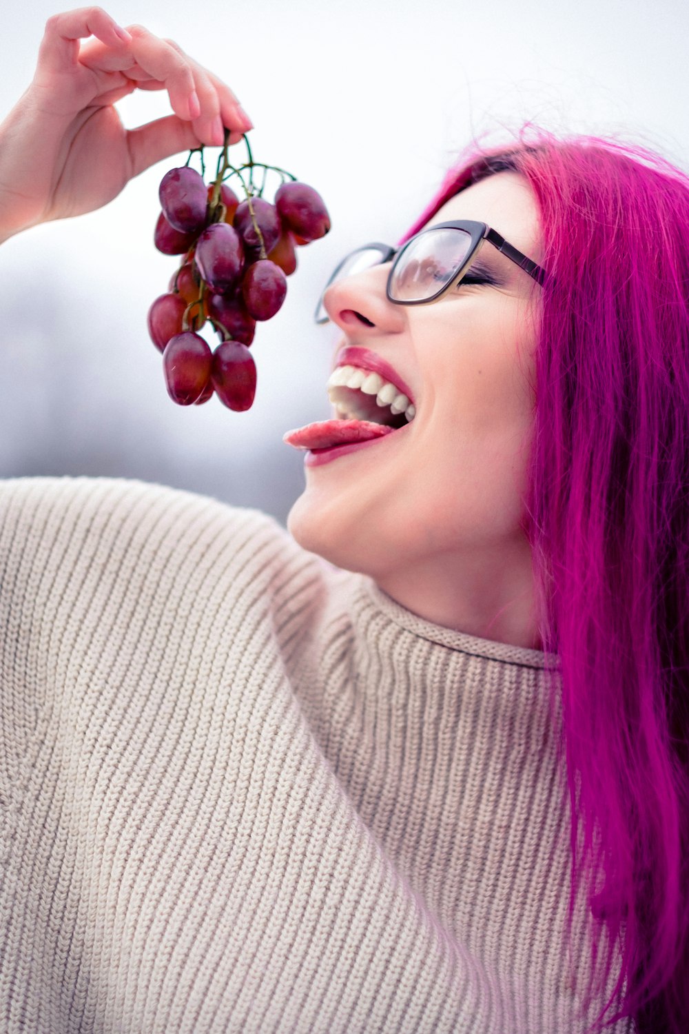 woman in gray sweater holding red round fruit