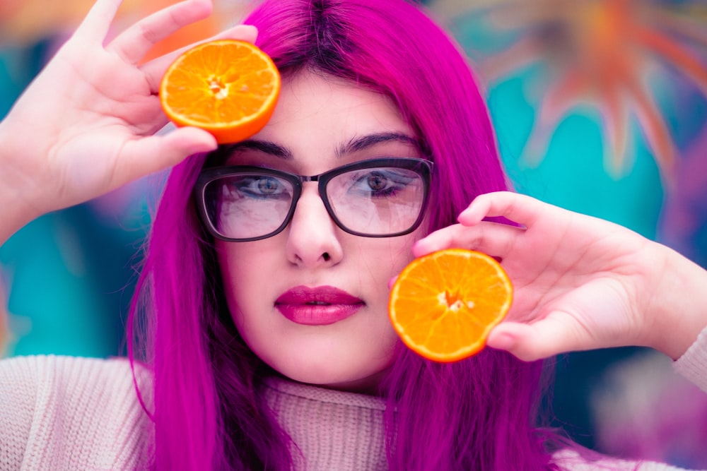 woman with red hair holding sliced orange