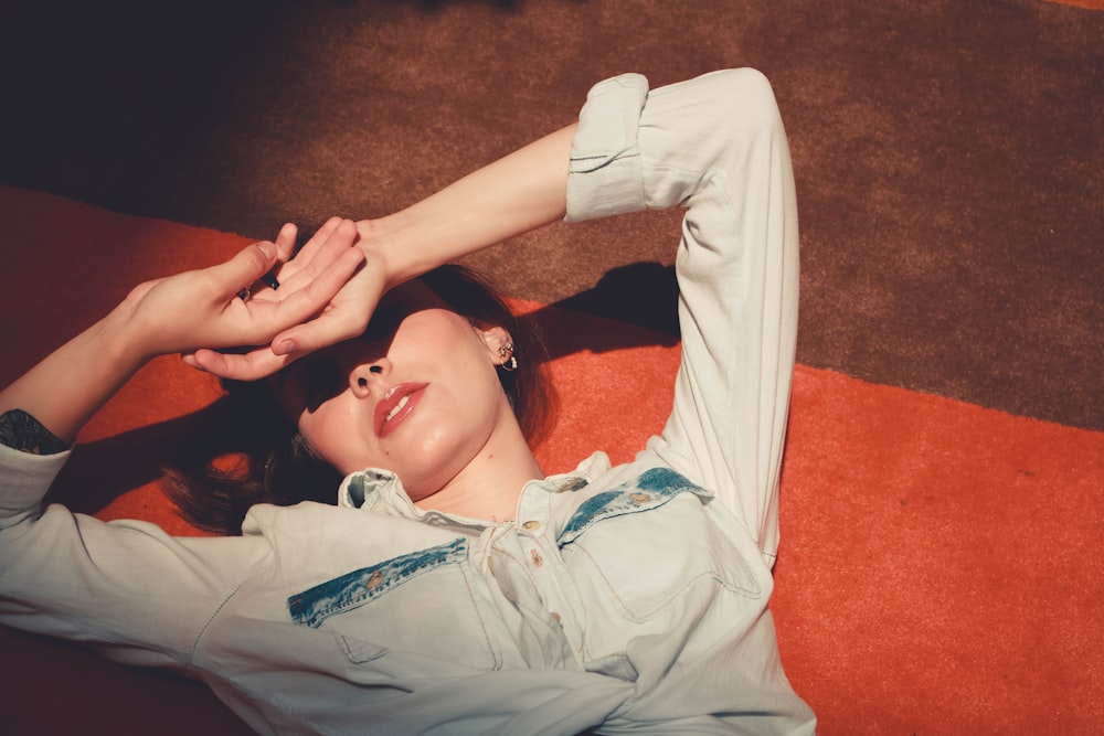 woman in gray button up shirt lying on red textile