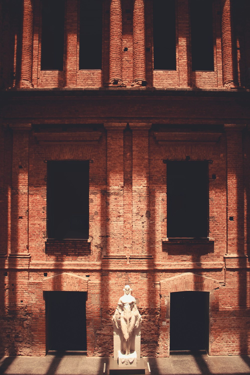 person in white shirt standing in front of brown brick building