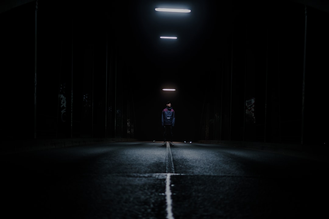 Man standing on a bridge at night.
