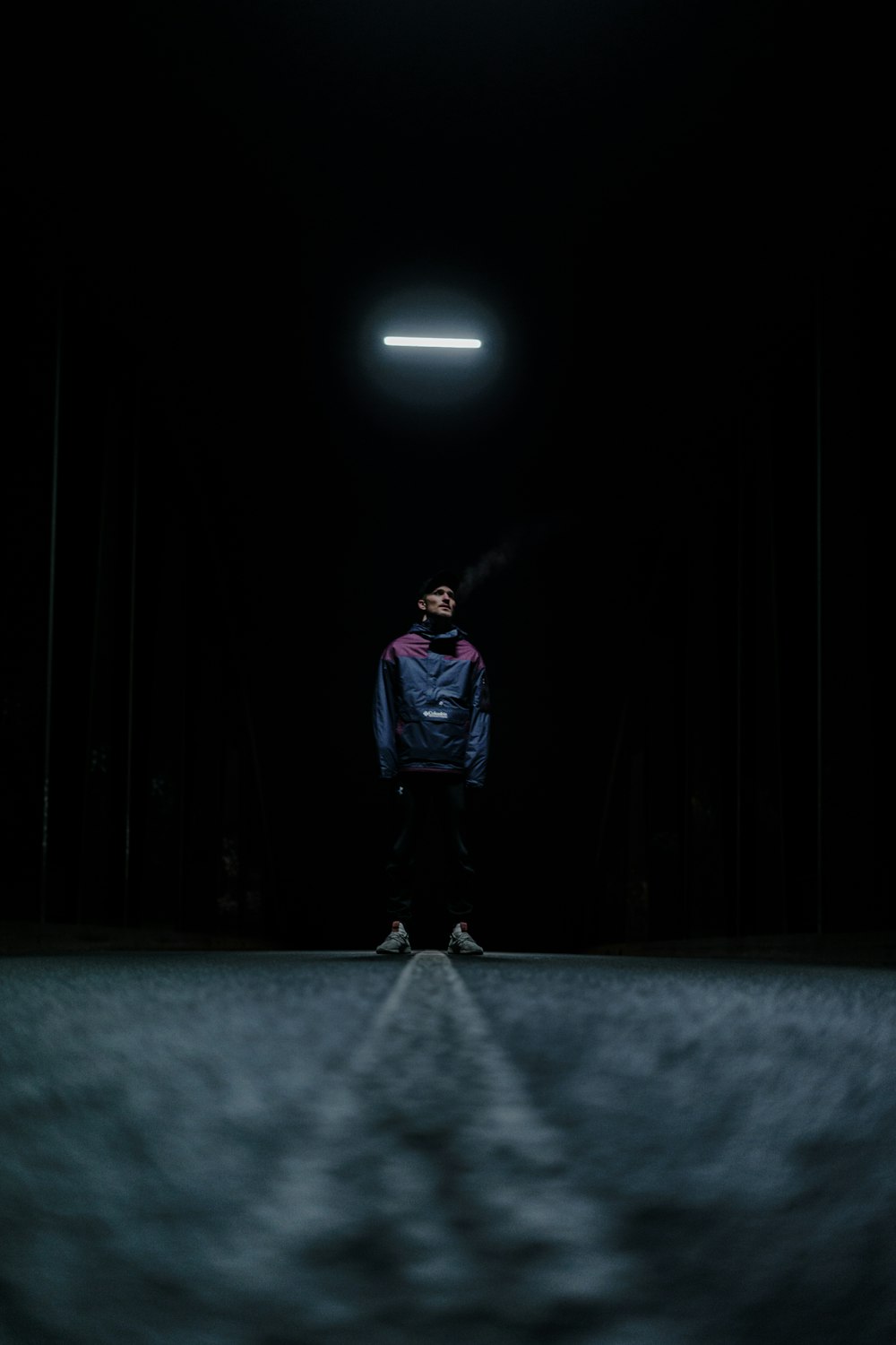 man in blue jacket standing on the middle of the road