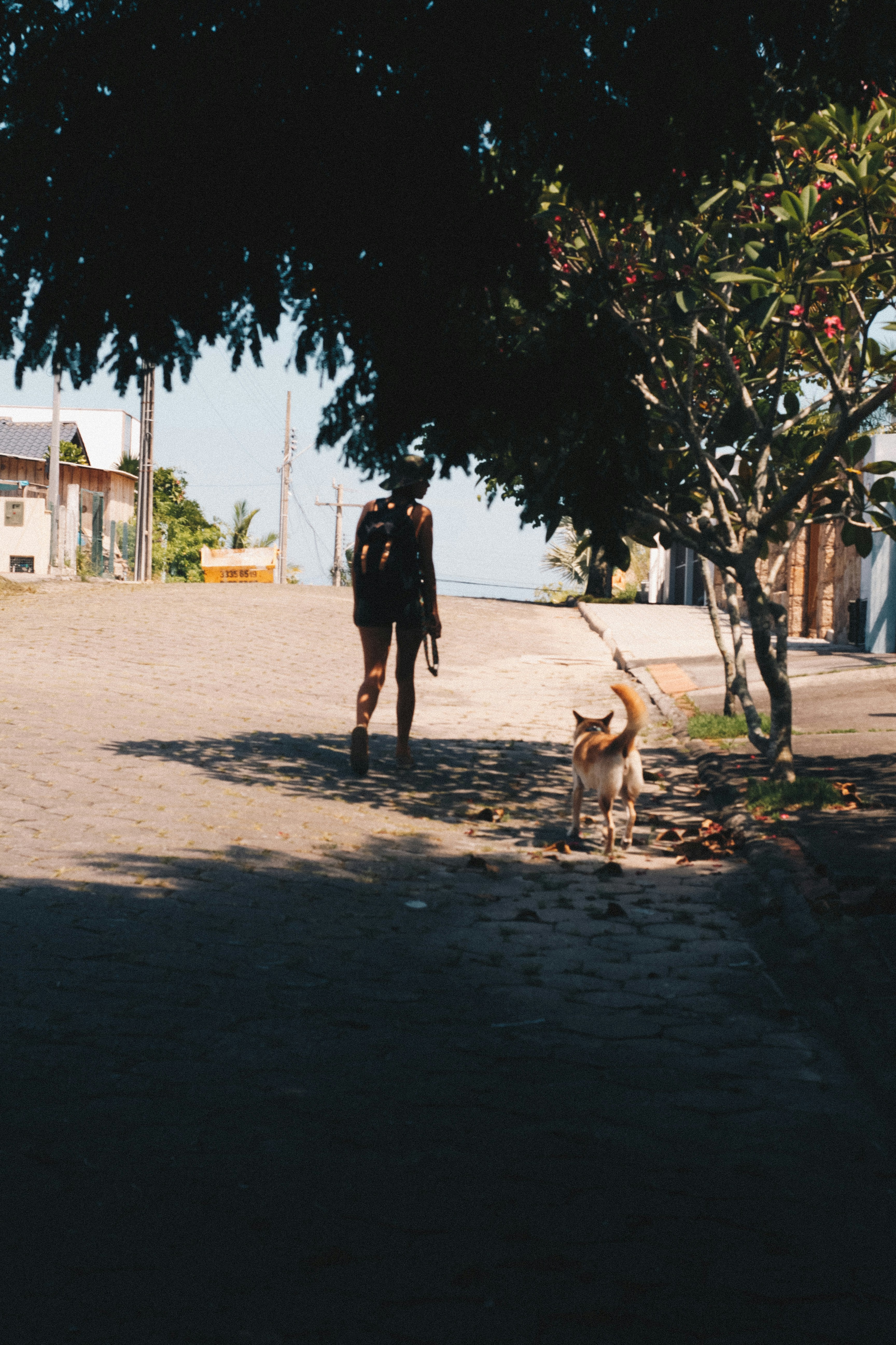 woman in black dress walking on gray sand during daytime