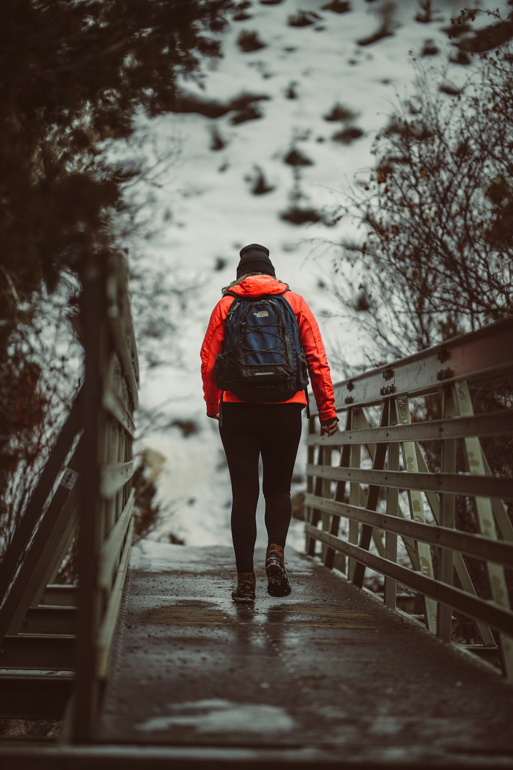 person in red and black jacket standing on snow covered pathway during daytime