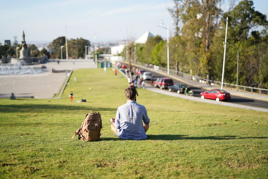 boy in white shirt sitting on green grass field during daytime