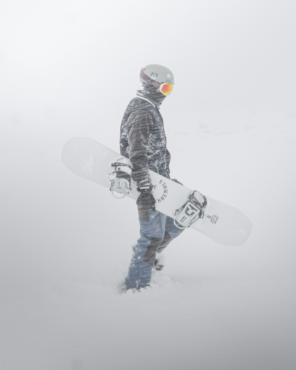 person in black and white pants and black snow shoes standing on snow covered ground during