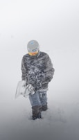 A sherpa carrying multiple pairs of skis and snowboards through fresh powder.
