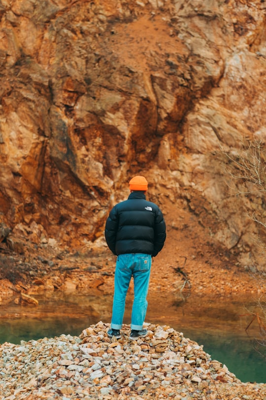 man in black jacket and blue denim jeans standing on brown rock formation during daytime in Vielsalm Belgium