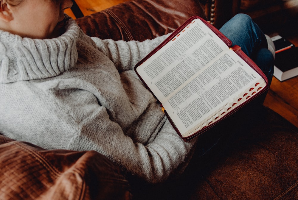 person in gray sweater reading book