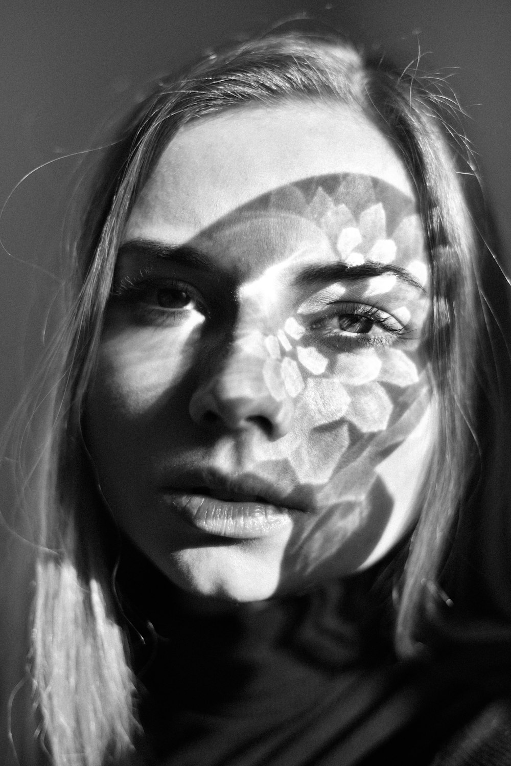 grayscale photo of woman with white and black floral face paint