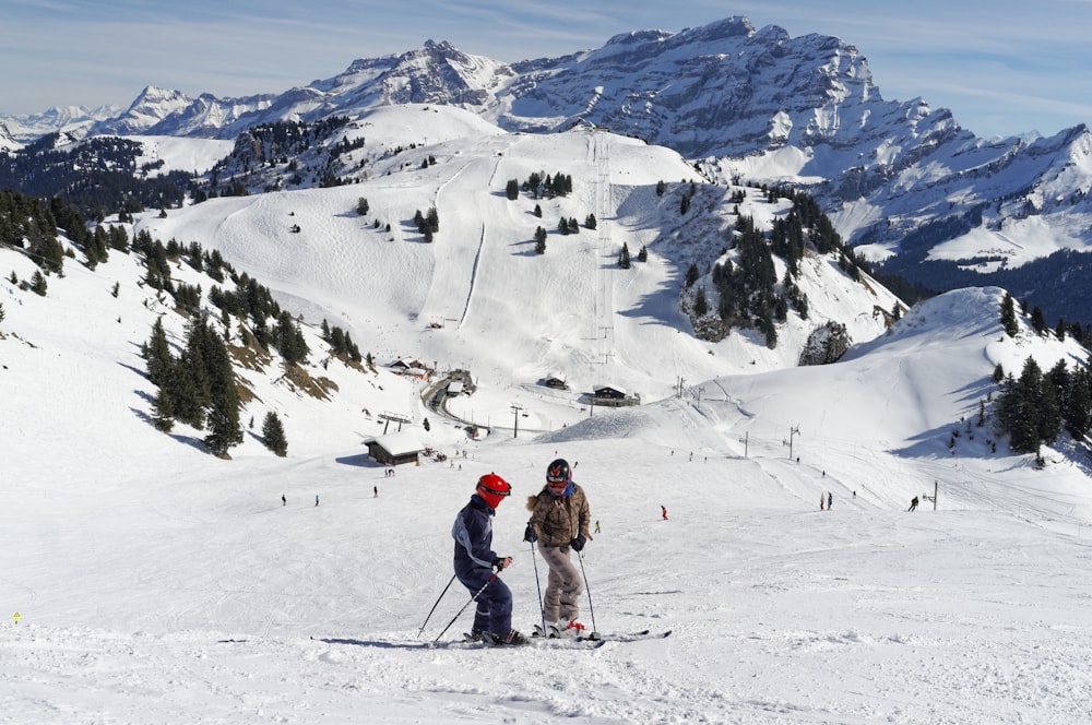 person in brown jacket and blue pants standing on snow covered mountain during daytime