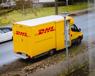 white and orange box truck parked near bare trees during daytime