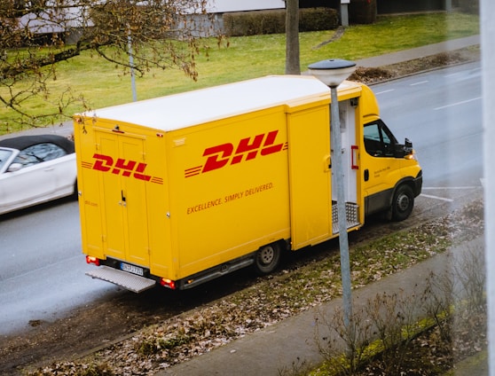 white and orange box truck parked near bare trees during daytime