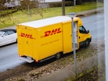 white and orange box truck parked near bare trees during daytime