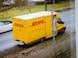white and orange box truck parked near bare trees during daytime