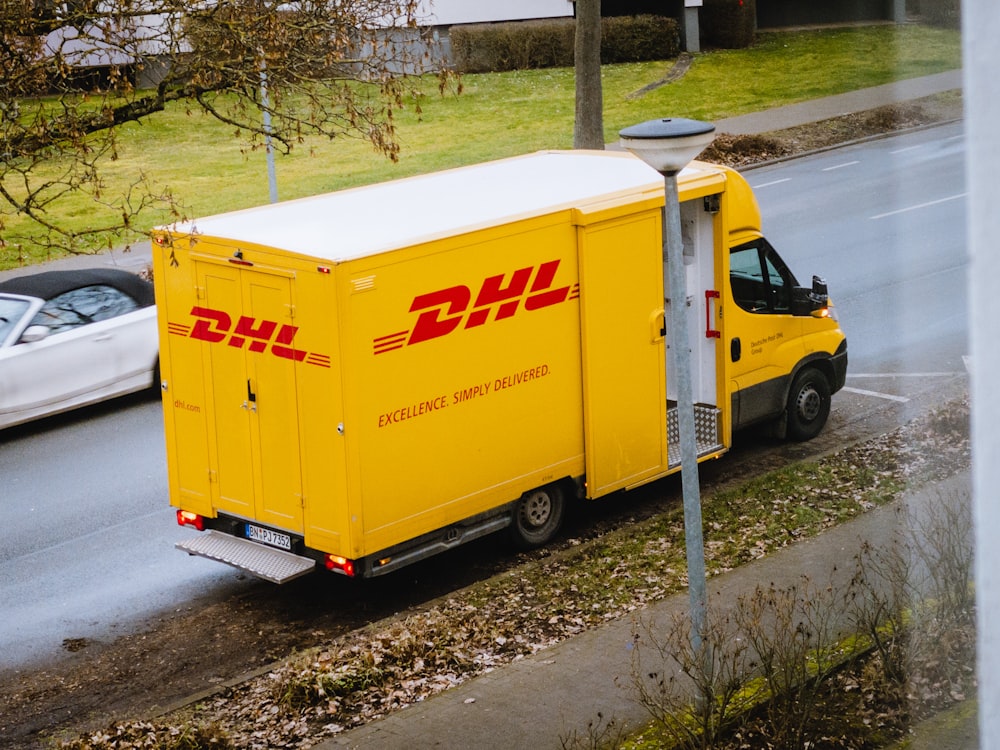 white and orange box truck parked near bare trees during daytime