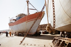 white and brown boat on white sand during daytime