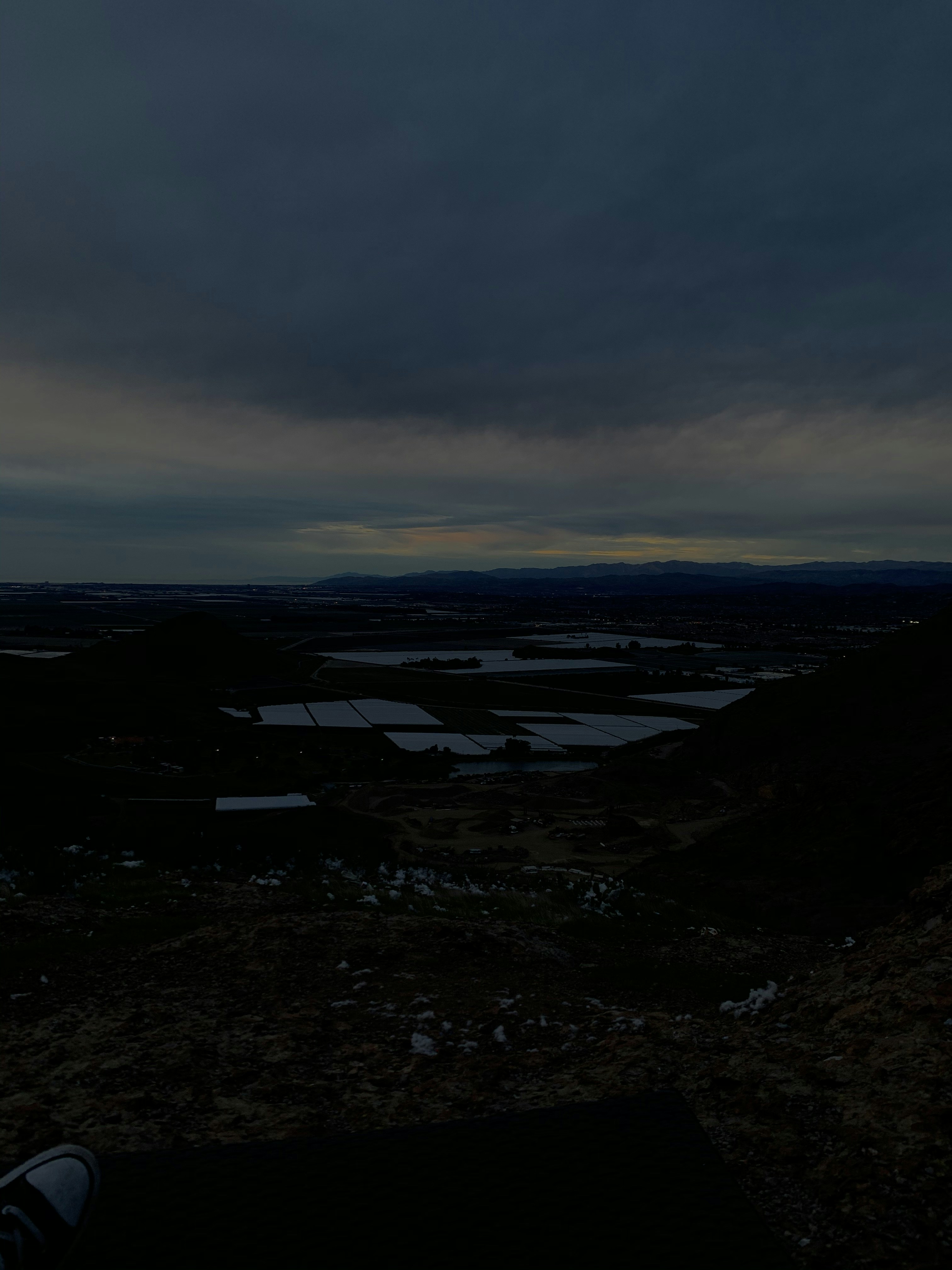 Moody dark country road at dusk with dramatic storm clouds, deep shadows, cool blue tones